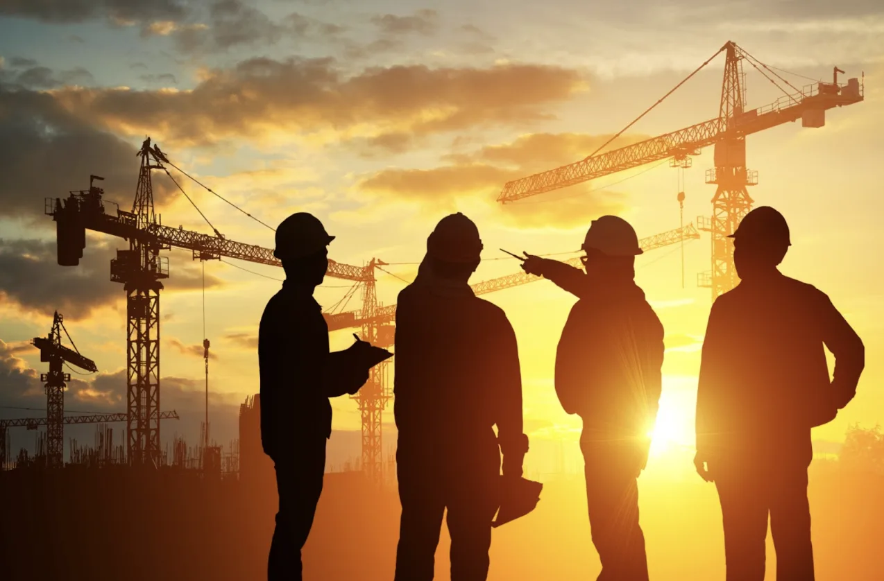 4 persone che osservano un cantiere al tramonto